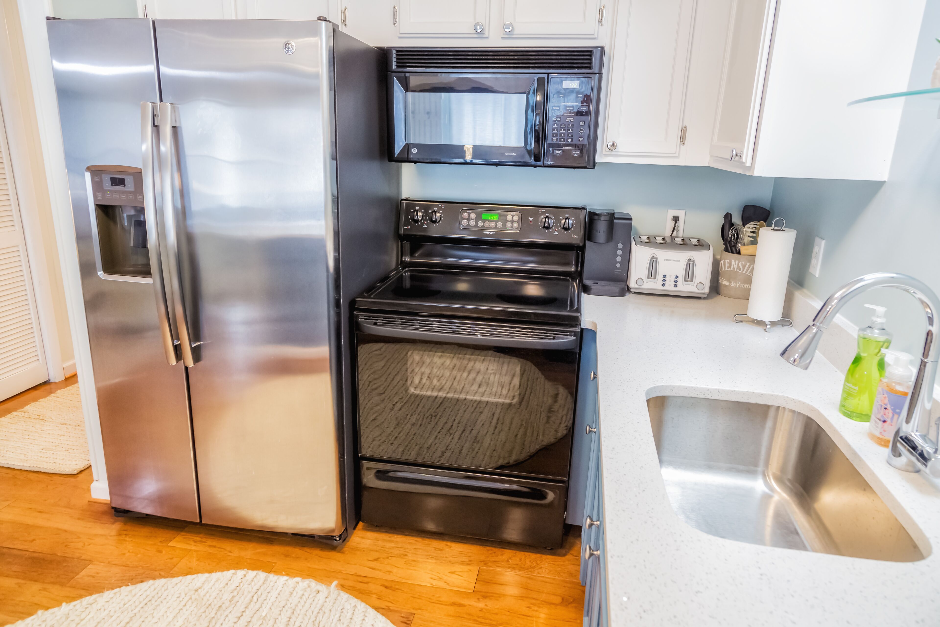 A compact kitchen with a stainless steel refrigerator, a microwave, and an oven.