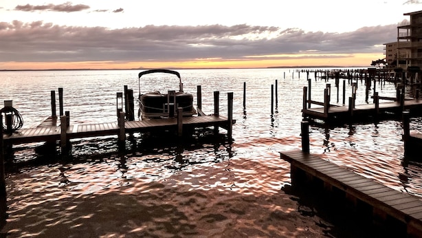 A wooden dock extending into calm waters with a boat moored at the end. - Top Rated! Beautifully Updated Bayside Condo with Pool! (Ocean City)
