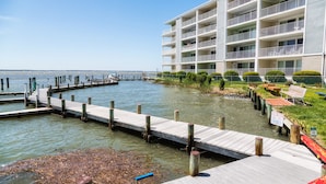 A waterfront hotel with a dock extending into the water, surrounded by greenery and a clear sky. - Top Rated! Beautifully Updated Bayside Condo with Pool! (Ocean City)