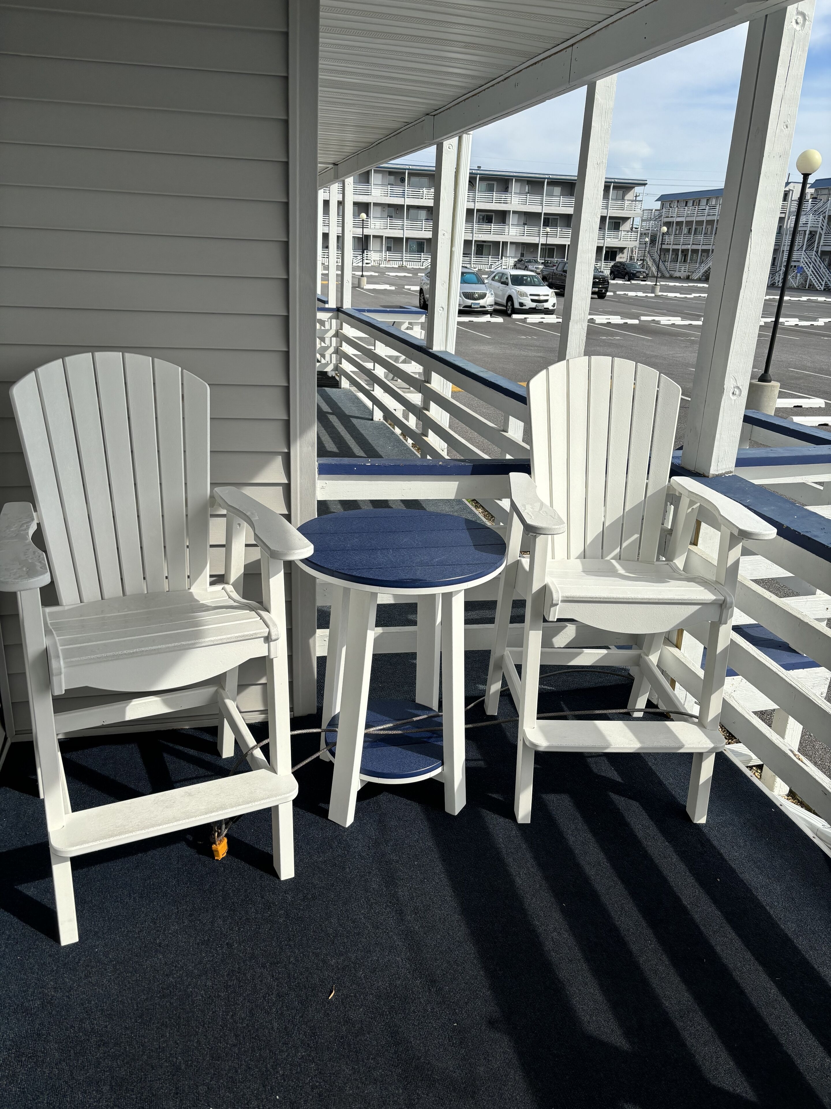 Un espace extérieur abrité avec deux chaises Adirondack blanches et une petite table ronde.