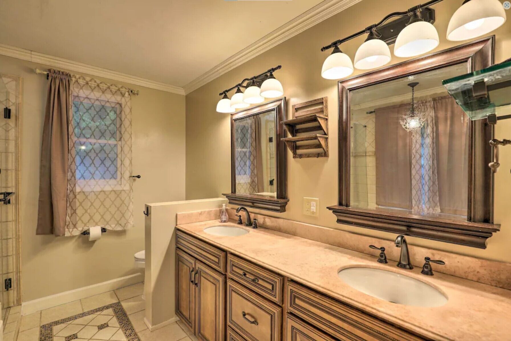Une salle de bain avec deux lavabos, un grand miroir et un espace douche.