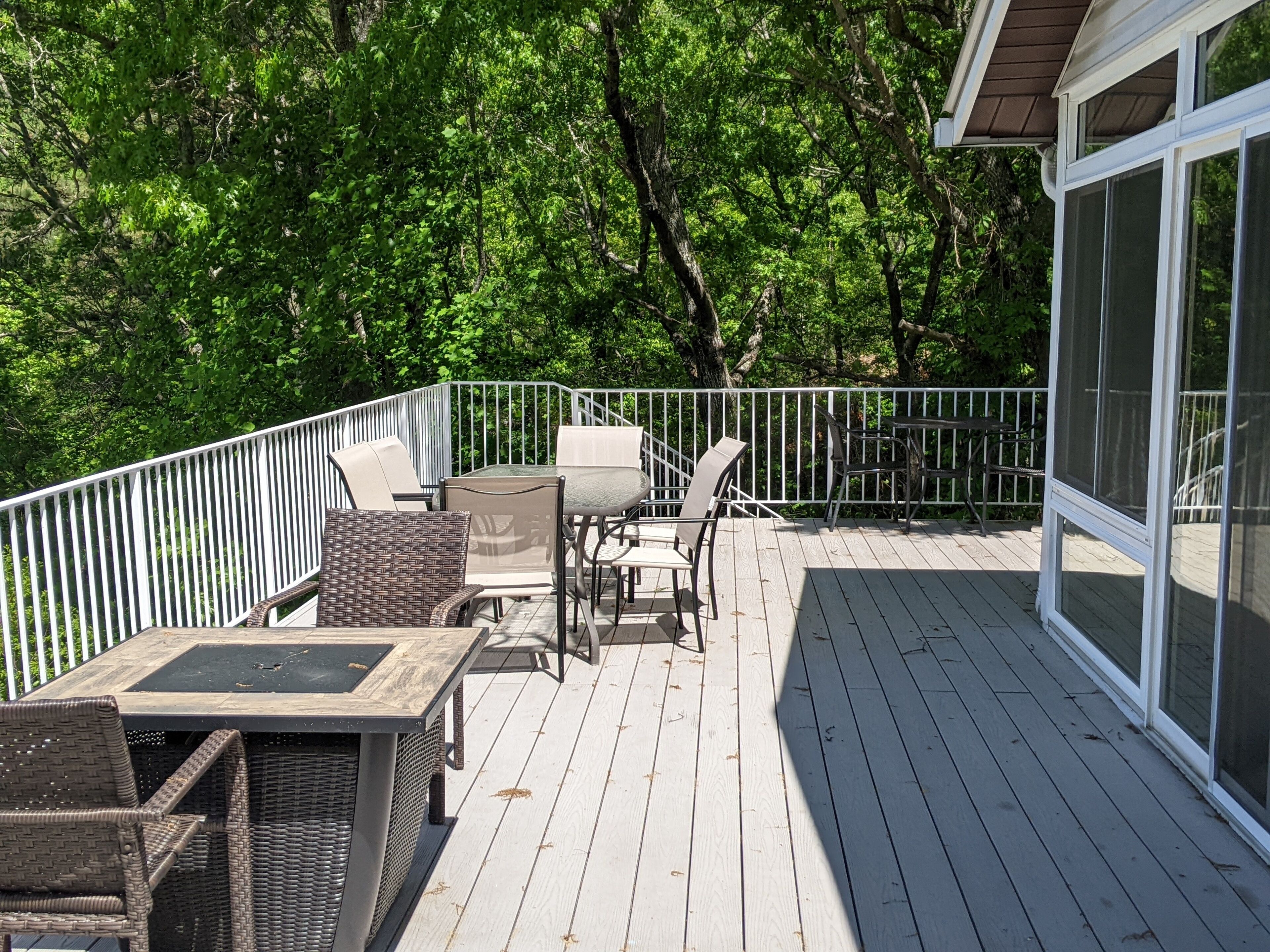 A deck with outdoor furniture, including chairs and a table, surrounded by a white railing.