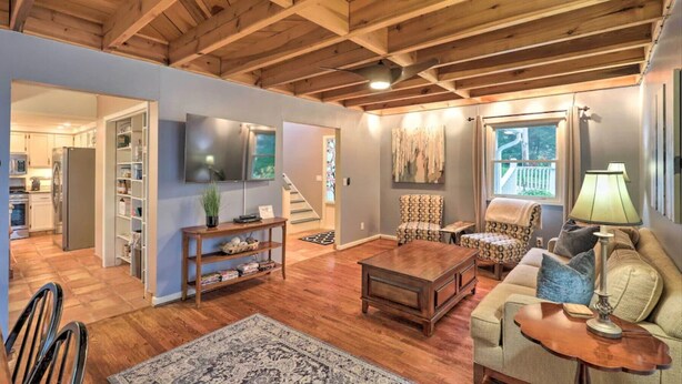 Un salon spacieux avec un plafond en bois, une télévision, un canapé, une table basse et un tapis à motifs.
