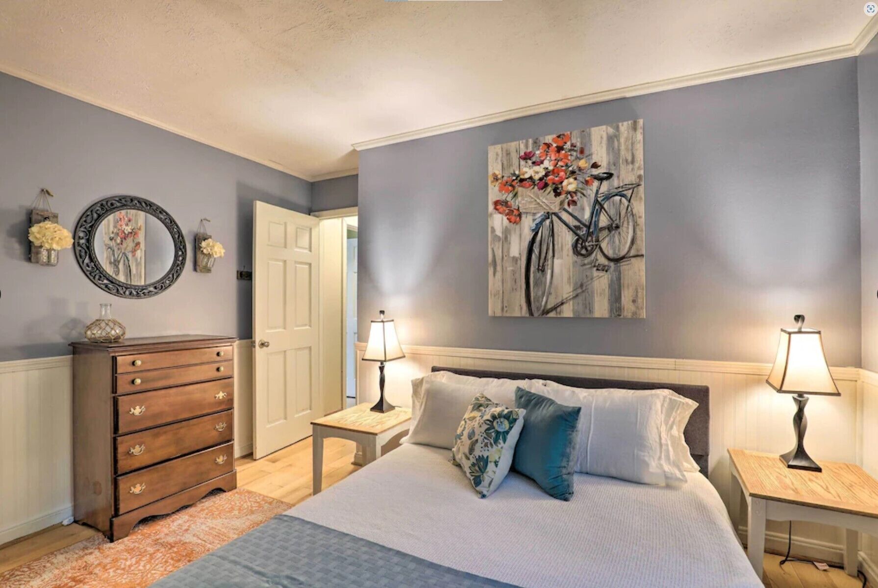 A bedroom with a bed, two bedside tables, a dresser, and a door.