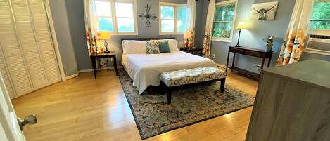 Une chambre à coucher avec un lit, des tables de chevet, un ventilateur de plafond et une fenêtre avec des rideaux.