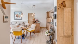 Eine moderne Küche mit Holzausstattung, ein Essbereich mit gelben Stühlen und einer dekorativen Bärenstatue.