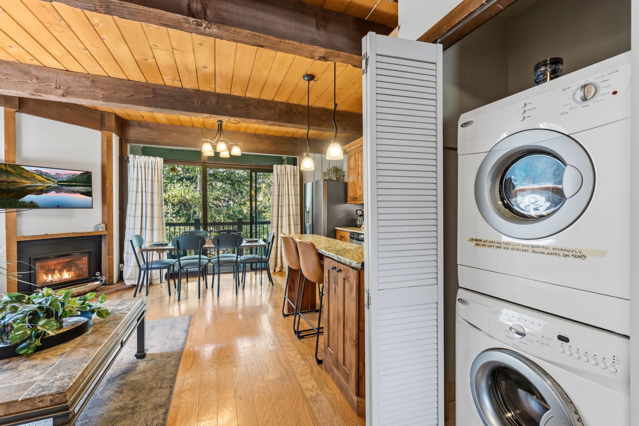 Una cocina moderna con lavadora integrada, piso de madera y comedor con vista al exterior.
