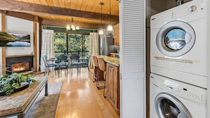 A modern kitchen with a built-in washing machine, wooden flooring, and a dining area with a view of the outdoors. - Cozy Breckenridge Condo Near Peak 9 & Main Street (Breckenridge)