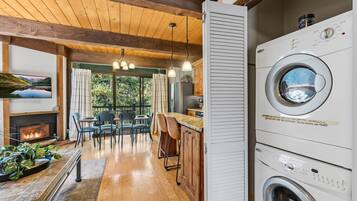 Una cocina moderna con lavadora integrada, piso de madera y comedor con vista al exterior.