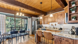 A modern kitchen with wooden cabinets, a granite countertop, and a dining area with a table and chairs. - Cozy Breckenridge Condo Near Peak 9 & Main Street (Breckenridge)