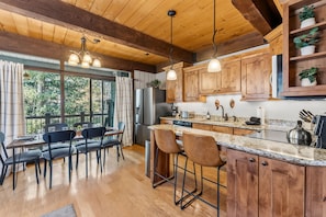 A modern kitchen with wooden cabinets, a granite countertop, and a dining area with a table and chairs. - Cozy Breckenridge Condo Near Peak 9 & Main Street (Breckenridge)