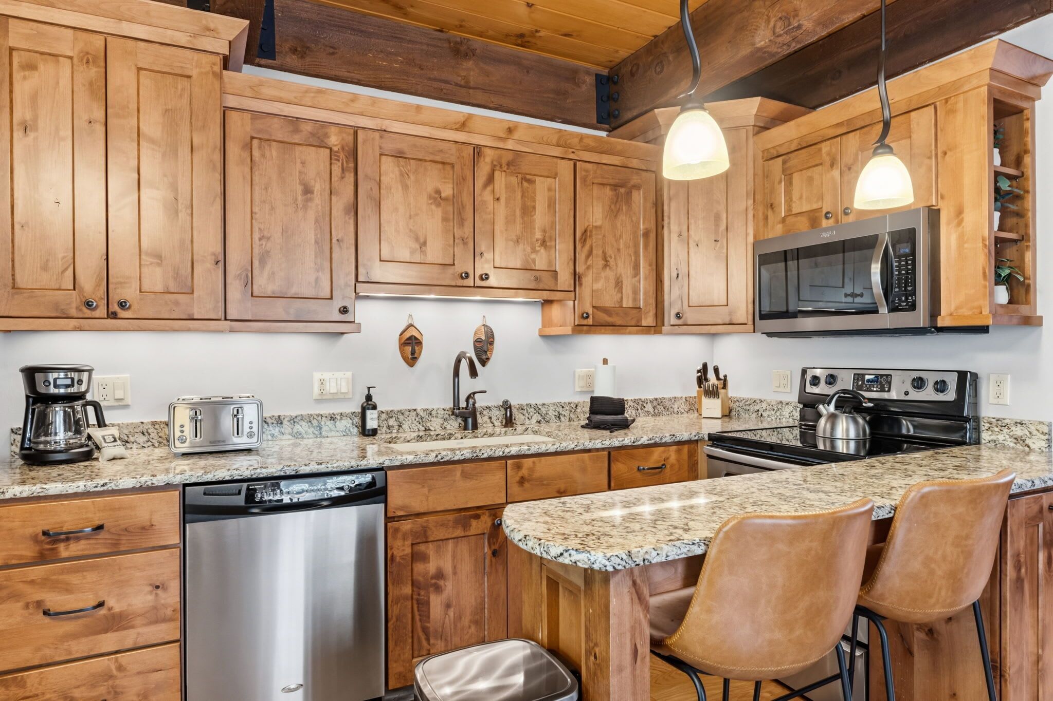 A kitchen with wooden cabinets, a microwave, a stove, a dishwasher, and a granite countertop.
