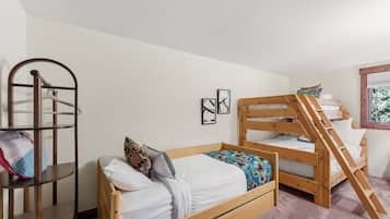 Una habitación con literas, una escalera de madera, un tendedero y dos cuadros en la pared.