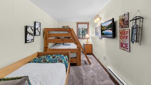 A bedroom with bunk beds, a TV, and various wall decorations. - Cozy Breckenridge Condo Near Peak 9 & Main Street (Breckenridge)