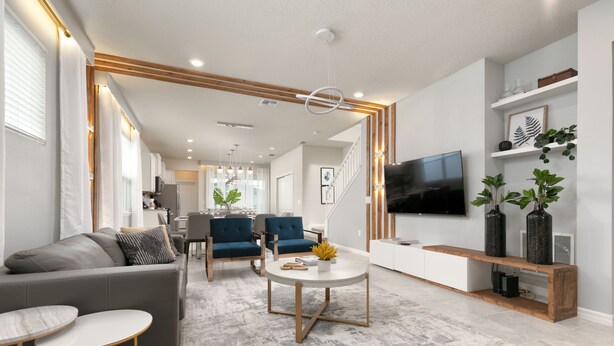 A modern living room with a grey sofa, blue chairs, a round coffee table, and a TV on the wall. - Capture Every Moment: Insta-Worthy 5BD, Theme Bd, Pv Pool, Avengers Game Room! (Davenport)