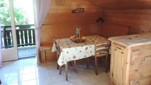Eine Holzhütte mit Esstisch für zwei Personen, einer kleinen Bank und einem Holzkabinett.
