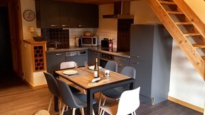 A modern kitchen with dark cabinets, a wooden dining table, and a built-in microwave.