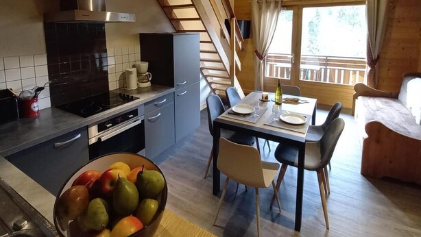 A compact kitchen with a dining area, wooden ceiling, and a view of the outdoors.