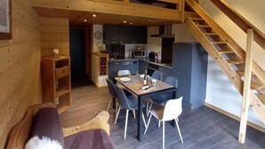 A cozy cabin interior with a dining area, kitchen, and a wooden staircase.