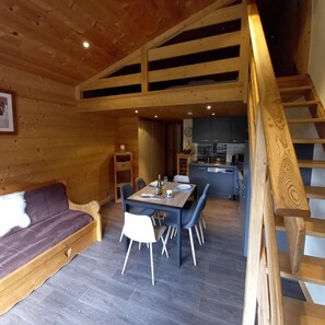 A wooden interior with a dining area, a sofa, and a kitchen.