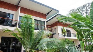 A modern building with a balcony, large windows, and lush greenery. - VillasLunaAfricana–101 (Puerto Viejo de Talamanca)