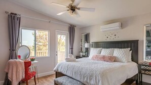 Una camera da letto con un letto, una toeletta con specchio, una ventola a soffitto e una finestra con tende.