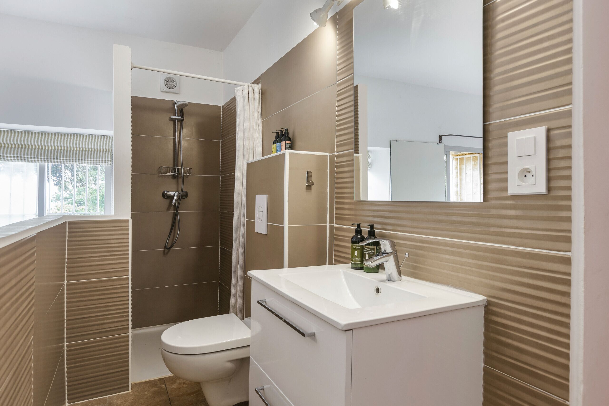 Et moderne badeværelse med brusebad, toilet og vaskebord.
