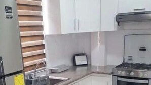 Une cuisine avec des armoires blanches, un réfrigérateur en acier inoxydable, une cuisinière et un four à micro-ondes.