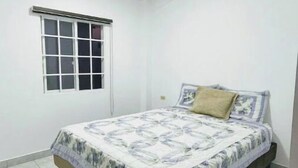 Une chambre à coucher avec un lit, une fenêtre et un sol carrelé.