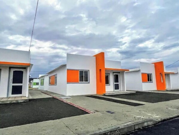 Une rangée de bâtiments modernes, blancs, avec des touches de couleur orange, caractérisés par de grandes fenêtres et des portes.