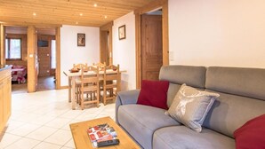 A cozy living room with a grey sofa, wooden dining table, and a coffee table. - 20m from ski slopes, 1st floor, balcony, parking, tv, 52m², Le Grand Bornand (Le Grand-Bornand)