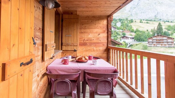 A wooden cabin with a balcony, a checkered table, and a mountain view. - 20m from ski slopes, 1st floor, balcony, parking, tv, 52m², Le Grand Bornand (Le Grand-Bornand)