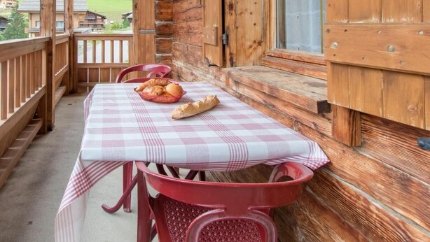 En træhytte med balkon, ternet dug og en kurv med brød.