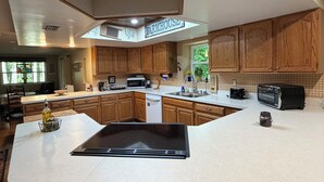 A modern kitchen with wooden cabinets, a large island, and a farmhouse sign. - Rose Creek Retreat (Franklin)
