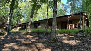 A rustic cabin with a porch, surrounded by trees and a forested area. - Rose Creek Retreat (Franklin)