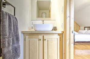Ein Badezimmer mit einem weißen Waschbecken, Holzschränken und einem Handtuch an der Wand.