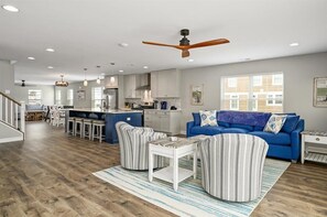 Un salón amplio con un sofá azul, sillones a rayas y una mesa de centro de madera.