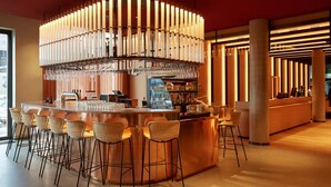 A bar area with a central bar counter, multiple stools, and a unique lighting fixture above.