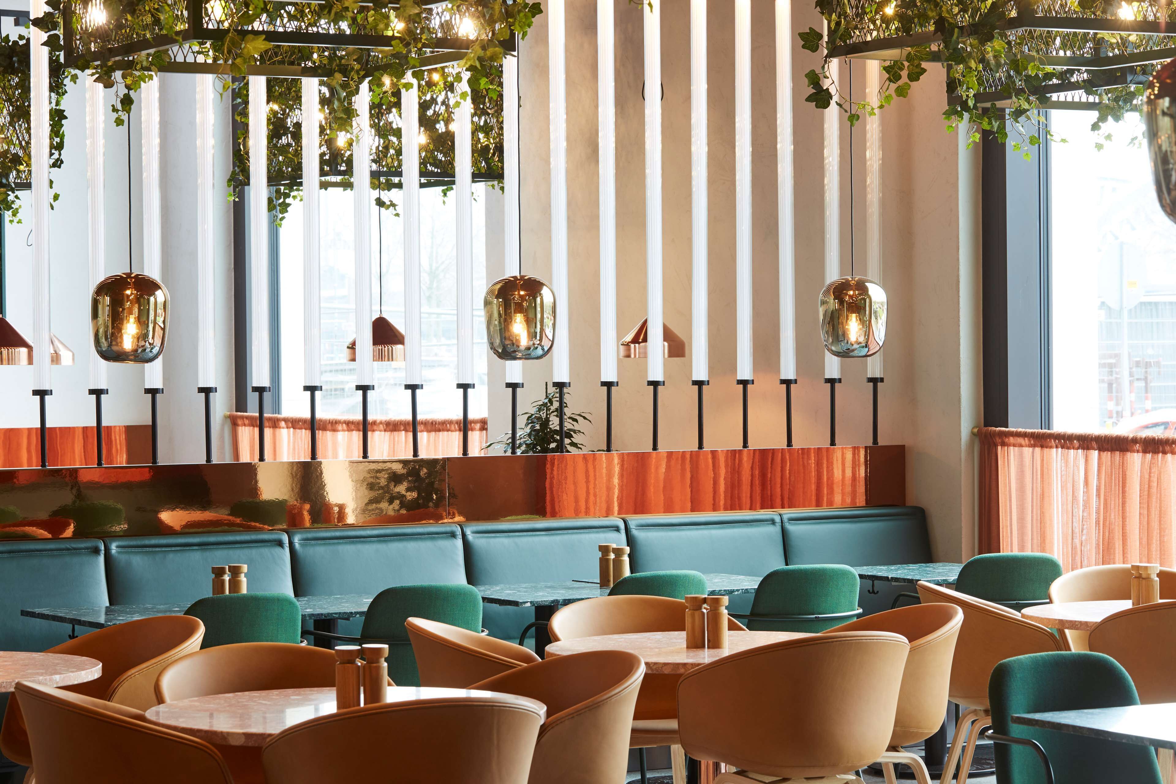 L'intérieur d'un restaurant avec des banquettes, des tables et des lampes suspendues.
