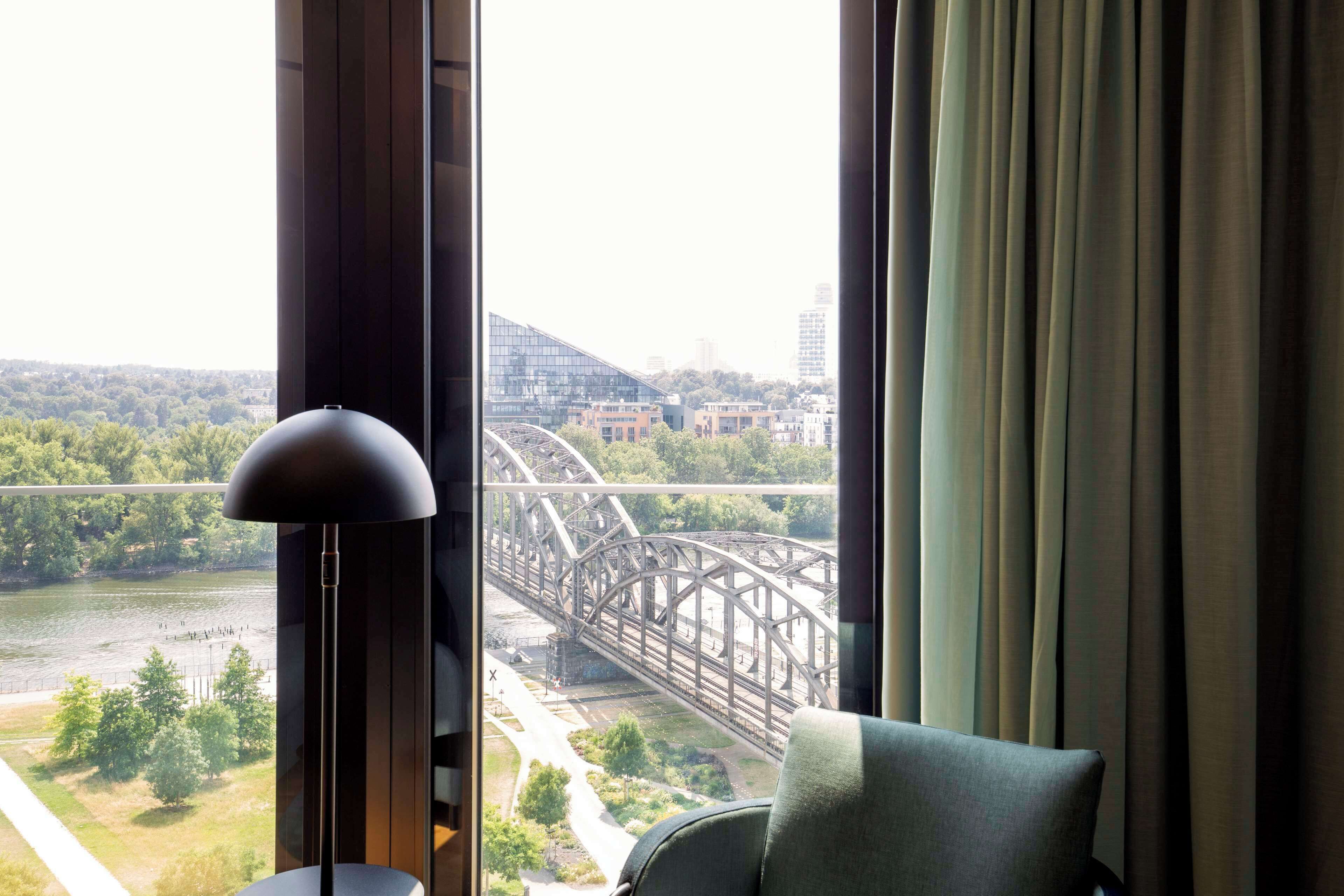 A room with a view of a bridge, a lamp, and a chair.