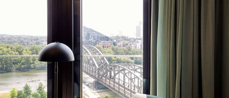 Una habitación con vista a un puente, una lámpara y una silla.