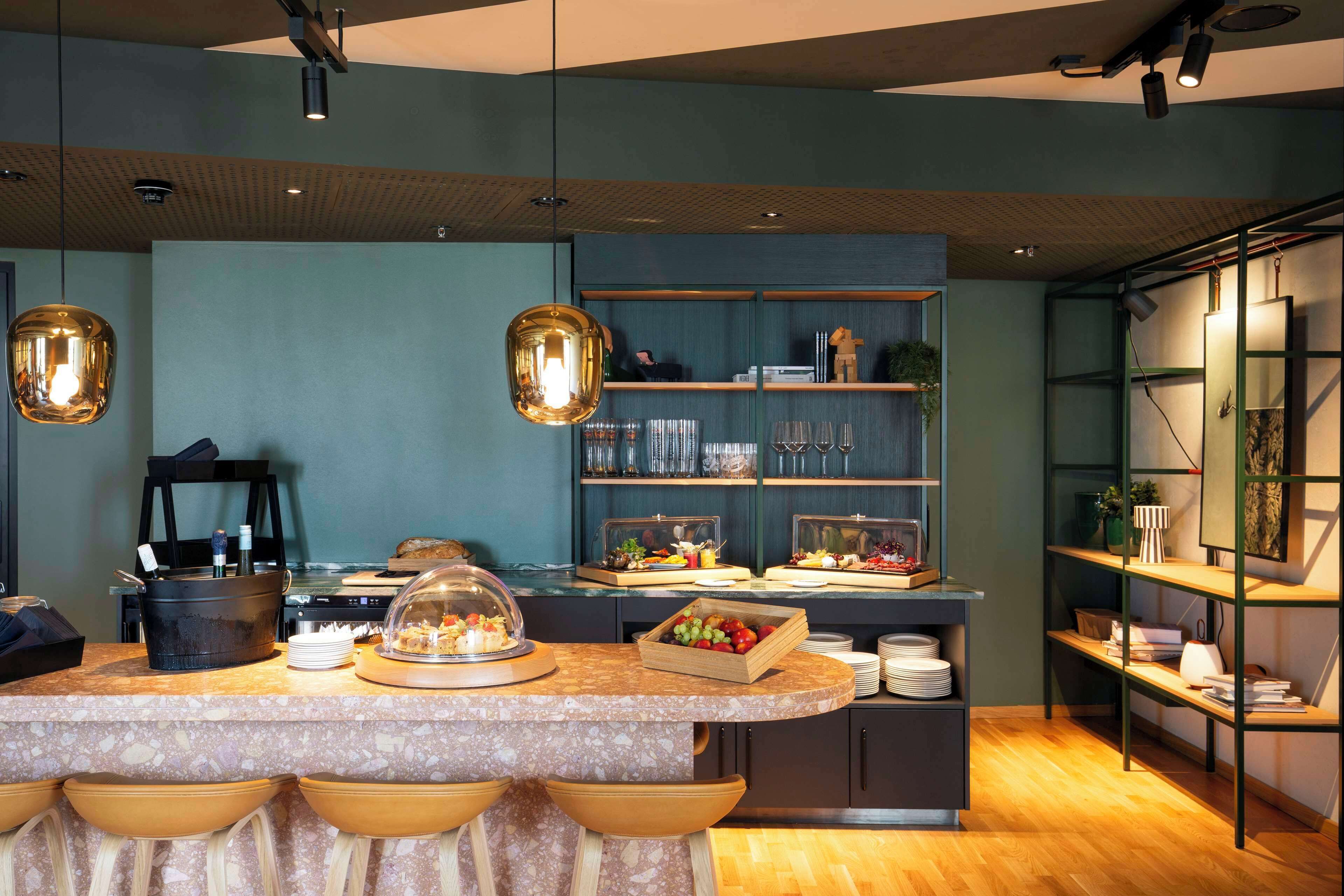 A modern kitchen with a marble countertop, a buffet setup, and a wooden bar area.