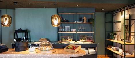 A modern kitchen with a marble countertop, a buffet setup, and a wooden bar area.