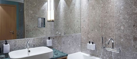 A modern bathroom with a double sink, a bathtub, and a large mirror.