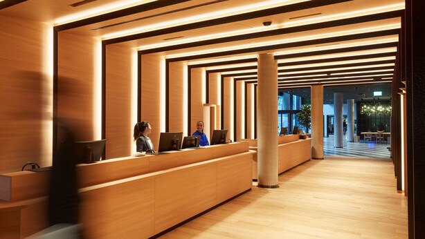 A modern reception area with wooden reception desks and a central column.