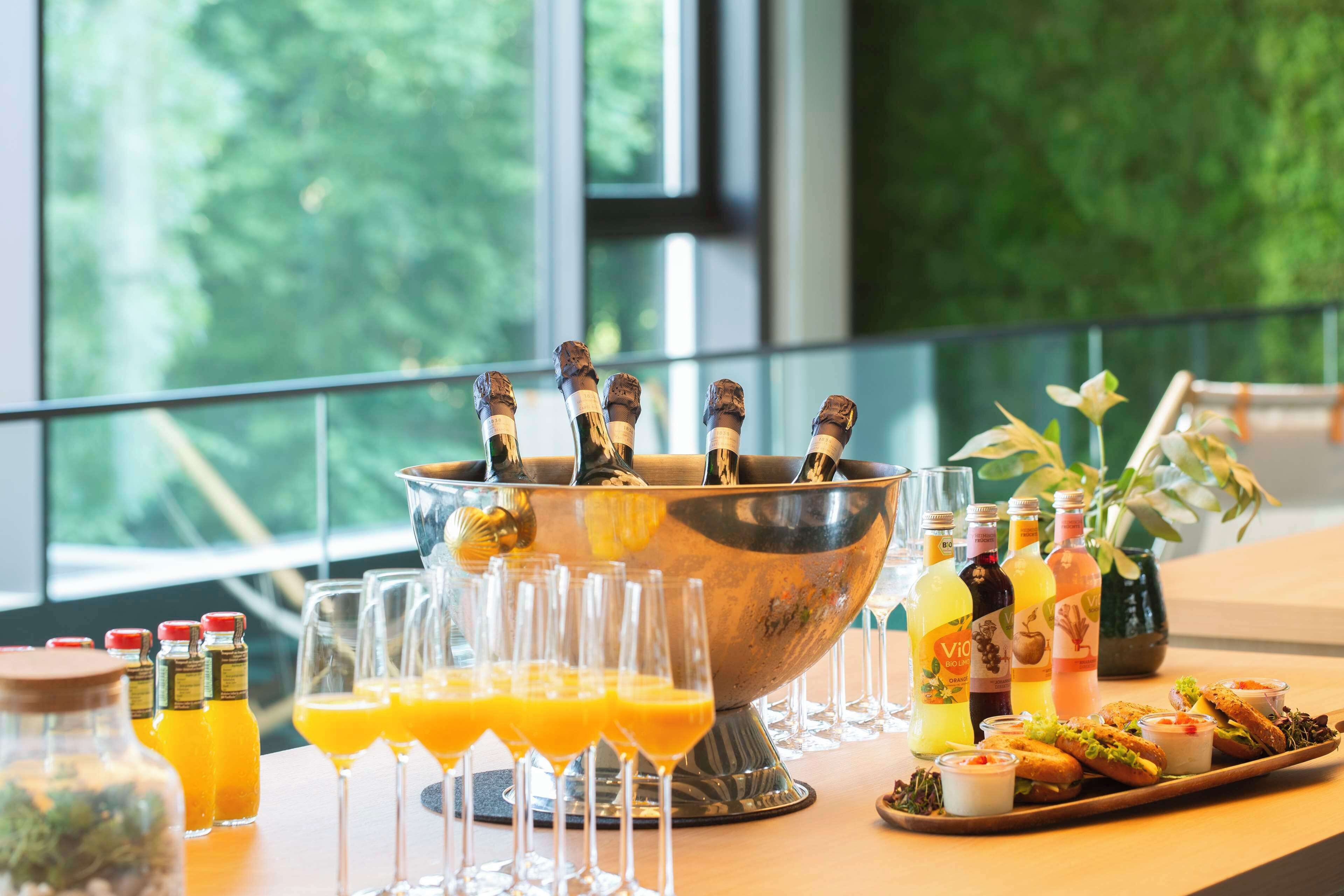 A bar area with a large metal bowl holding bottles, glasses filled with orange juice, and a tray of food.