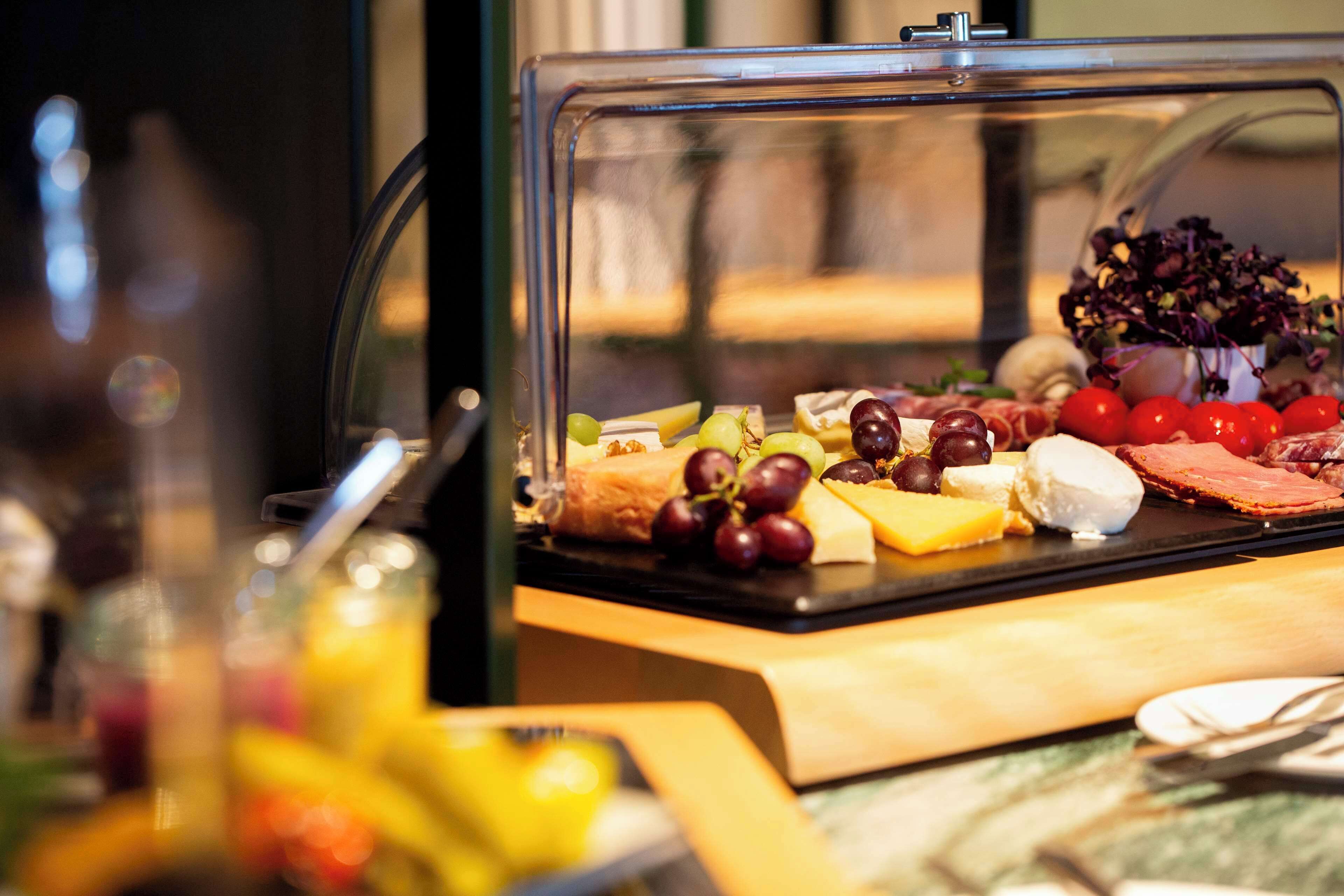 A buffet with various cheeses, fruits, and meats.