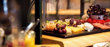 A buffet with various cheeses, fruits, and meats.