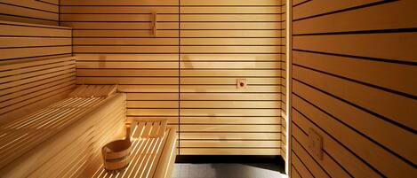 A sauna room with wooden slats, benches, and a bucket.