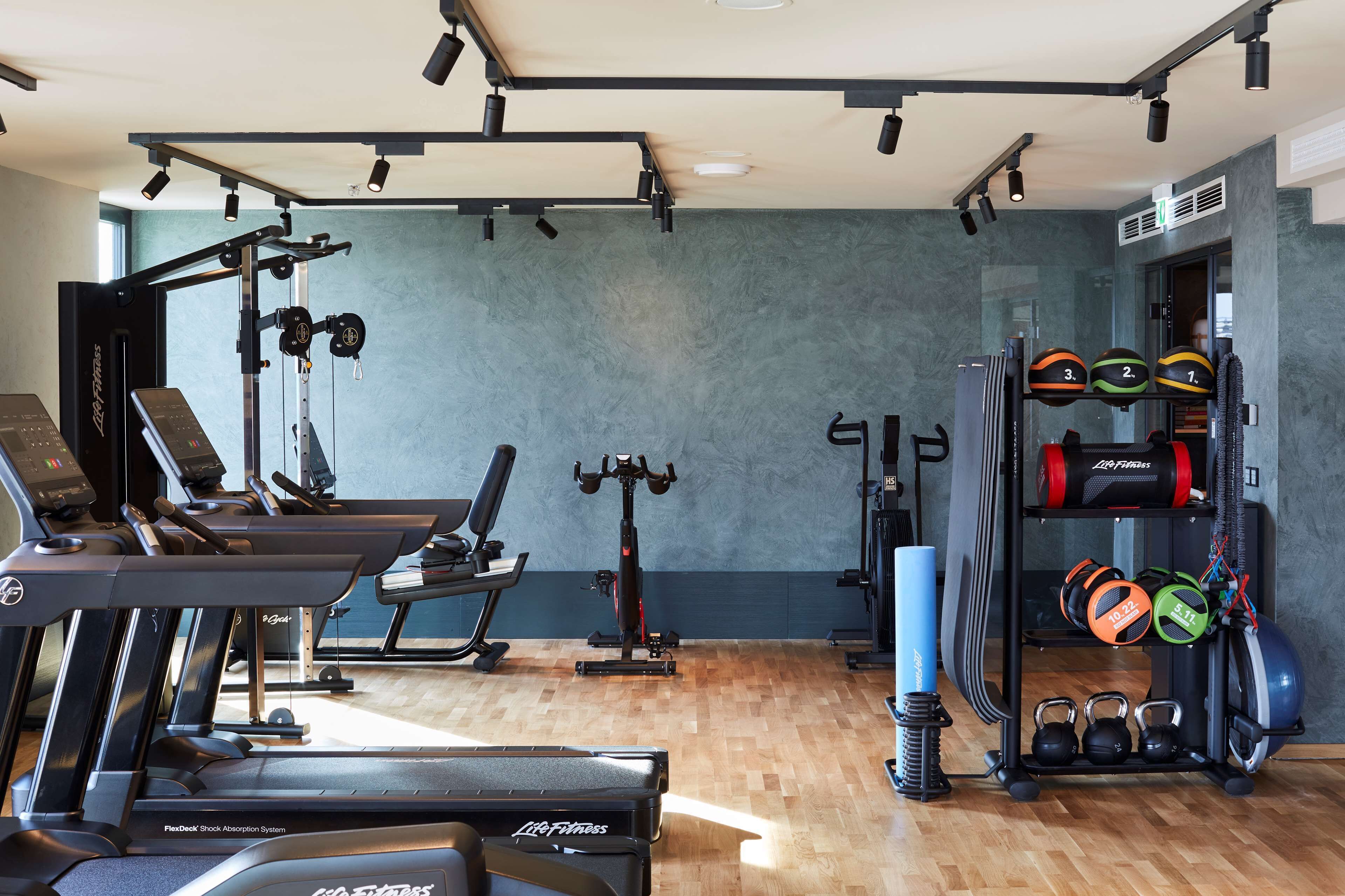 Ein Fitnessstudio mit Laufbändern, Kraftgeräten und verschiedenen Trainingsmöglichkeiten.
